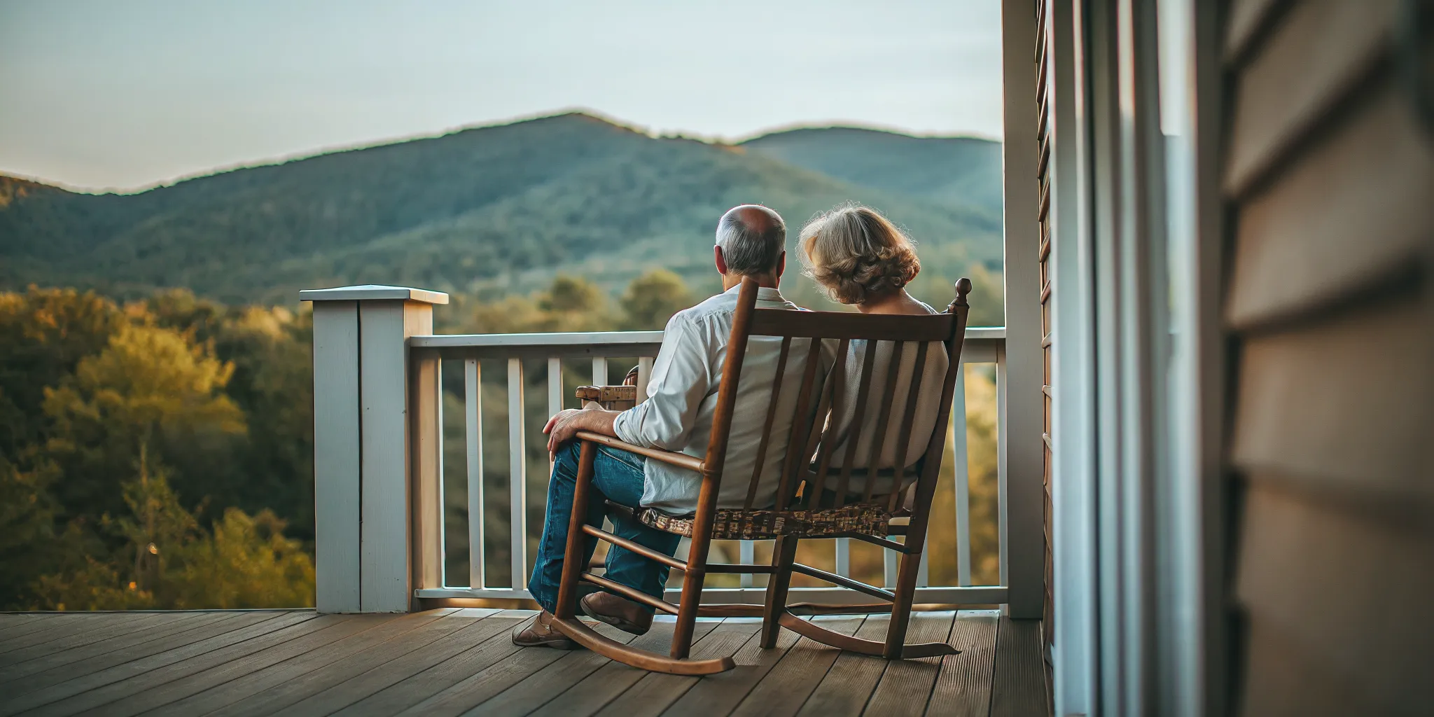 Retired couple reviewing insurance documents on a tablet while sitting on a porch overlooking West Virginia mountains